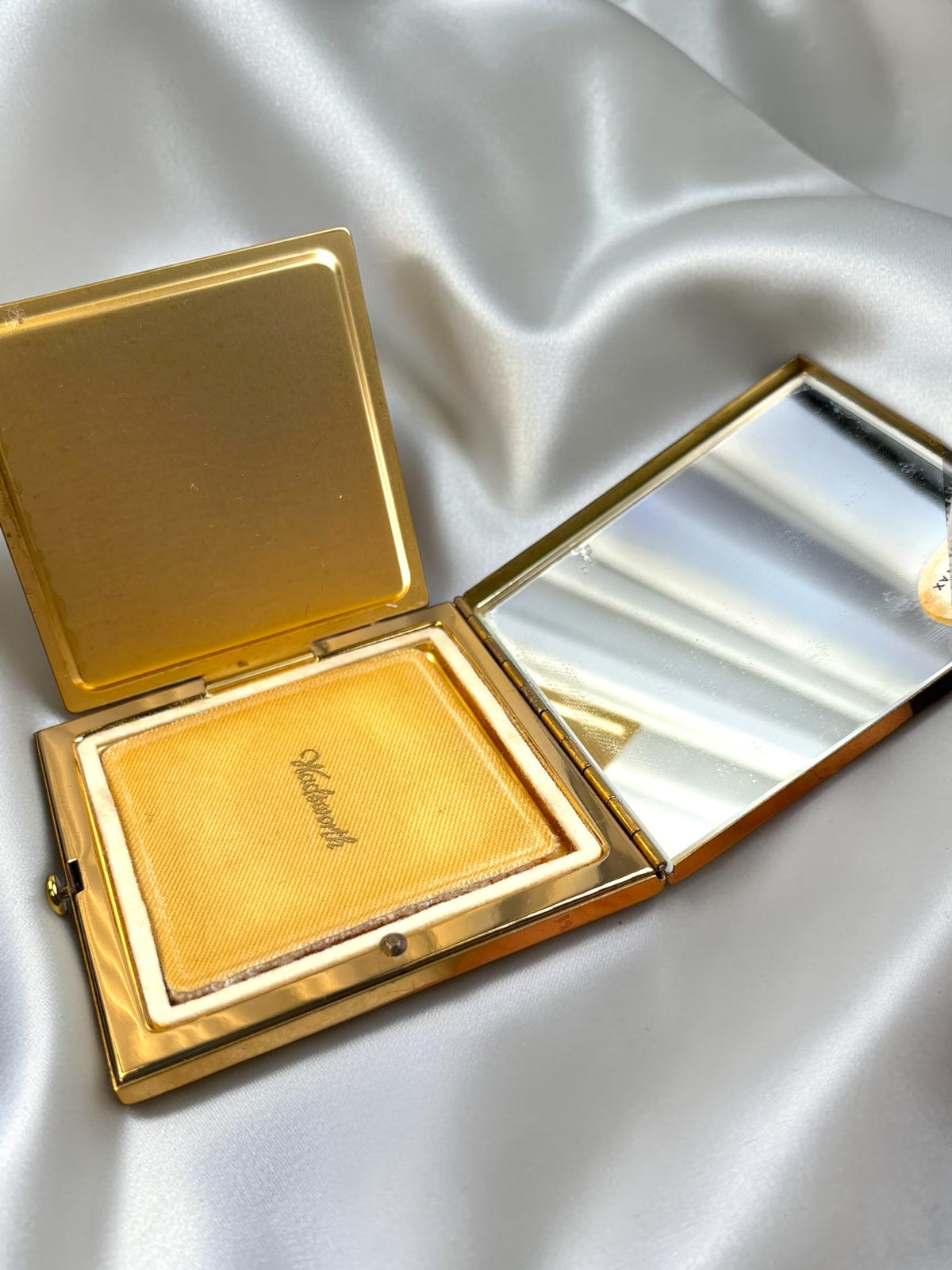 Vintage gold-tone Wadsworth powder compact open, showing powder and mirror.