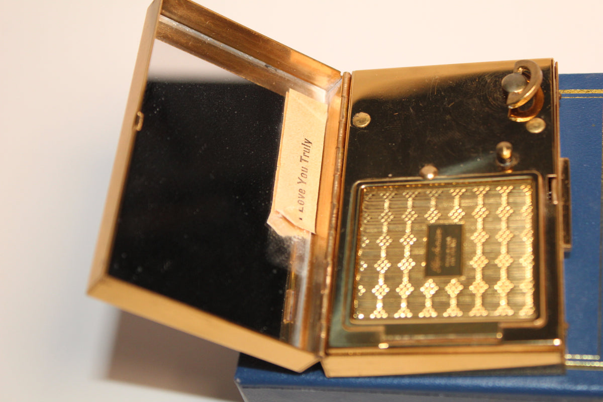 Gold musical compact open to reveal a mirror and a note that says 'Love You Truly'.