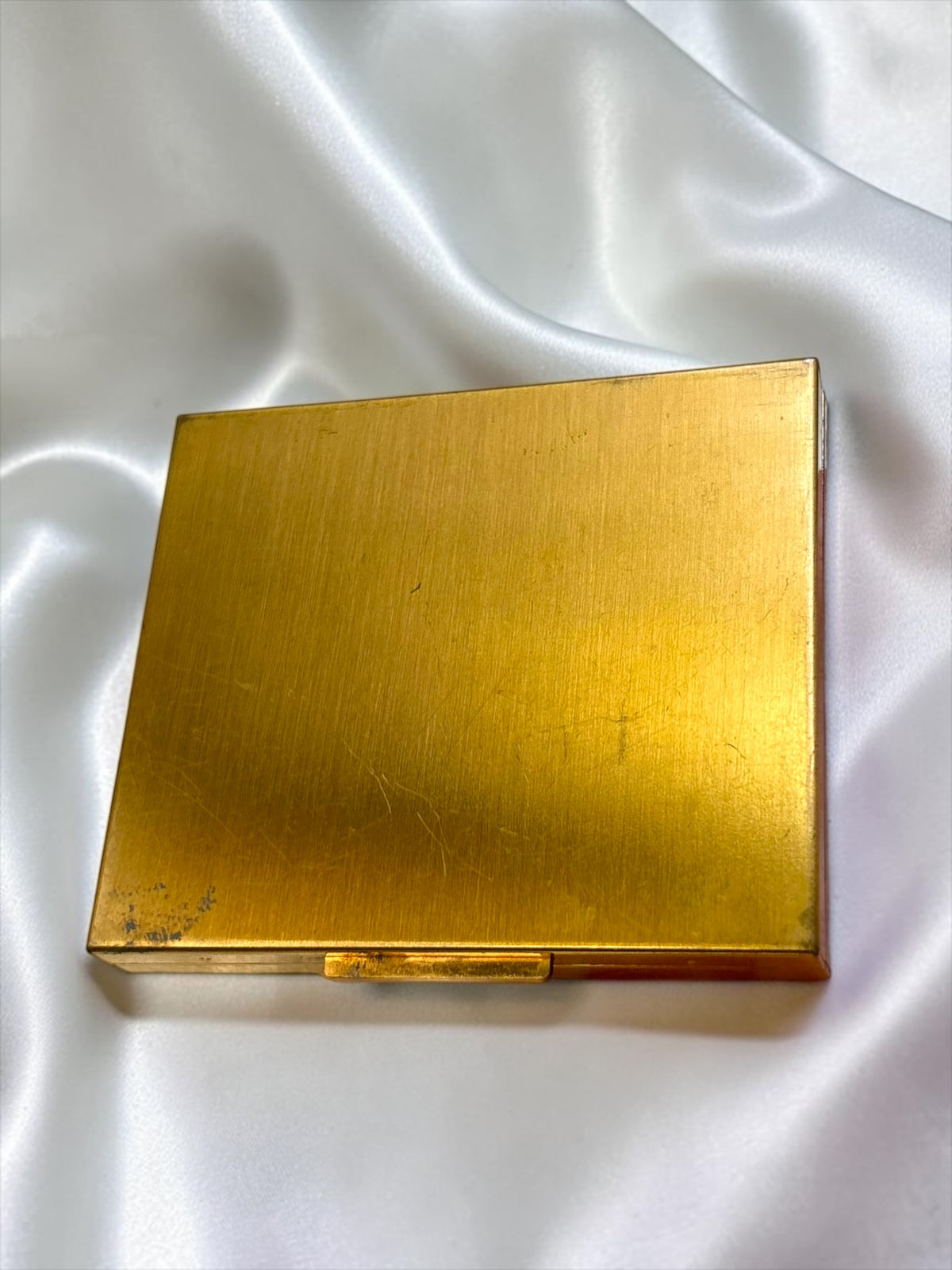 Vintage Ritz gold-tone powder compact with rhinestone floral detail, showing patina and wear.