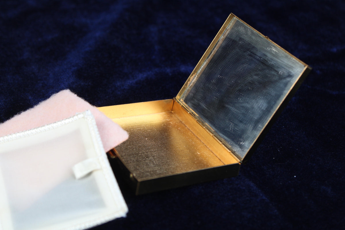 1950s gold-tone powder compact with mirror and powder compartment, open.