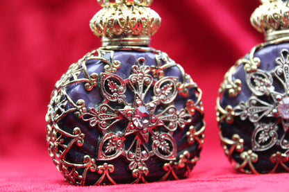 Matched pair of amethyst glass perfume bottles with gold filigree and rhinestone details.