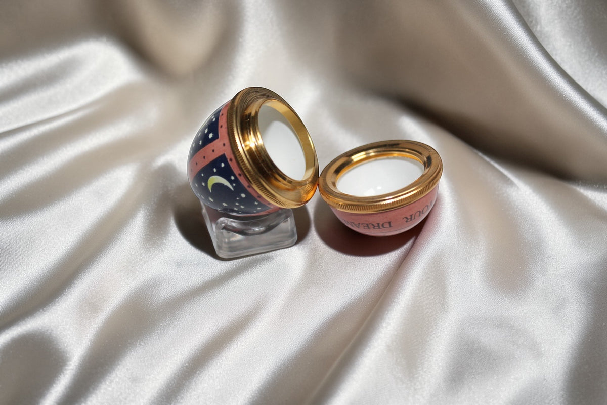 Halcyon Days navy egg trinket box with moon and stars design, open to show gold rim.