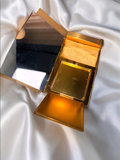 Gold-tone vintage Volupte carryall compact with mirror, powder compartment, and puff.