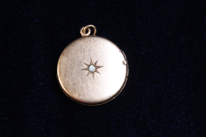 Gold plated locket with a starburst design and a central stone, on a dark background.