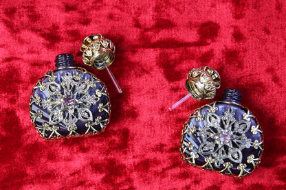 Matched pair of amethyst glass perfume bottles with gold filigree and rhinestone details on red velvet.