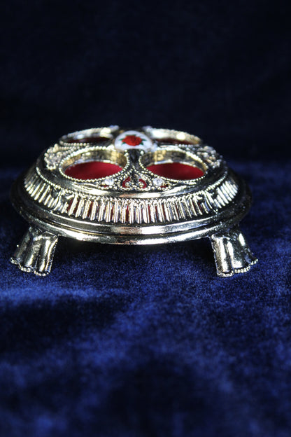 Gold lipstick holder with red velvet interior and an enchanted rose design.