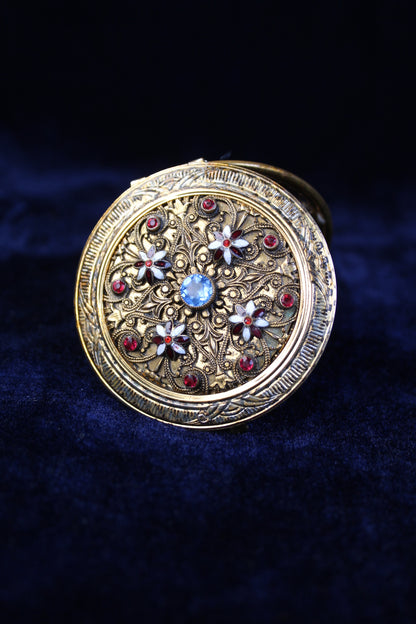 Ornate gold-tone 1920s filigree mesh purse compact case with red and blue glass accents.