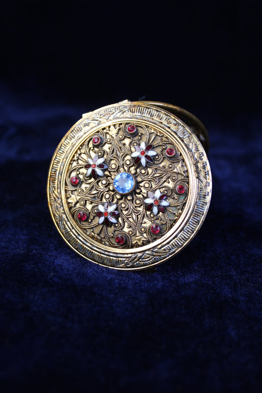 Ornate gold-tone 1920s filigree mesh purse compact case with red and blue glass accents.