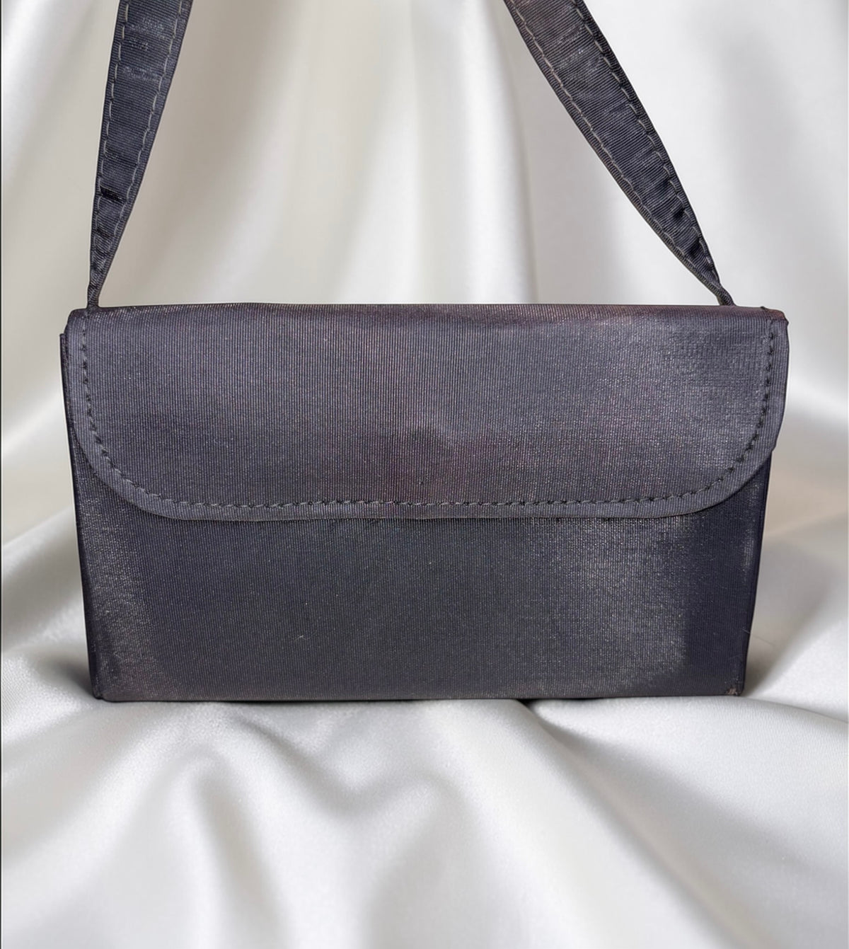 Dark gray fabric clutch purse with a flap closure and a thin strap.