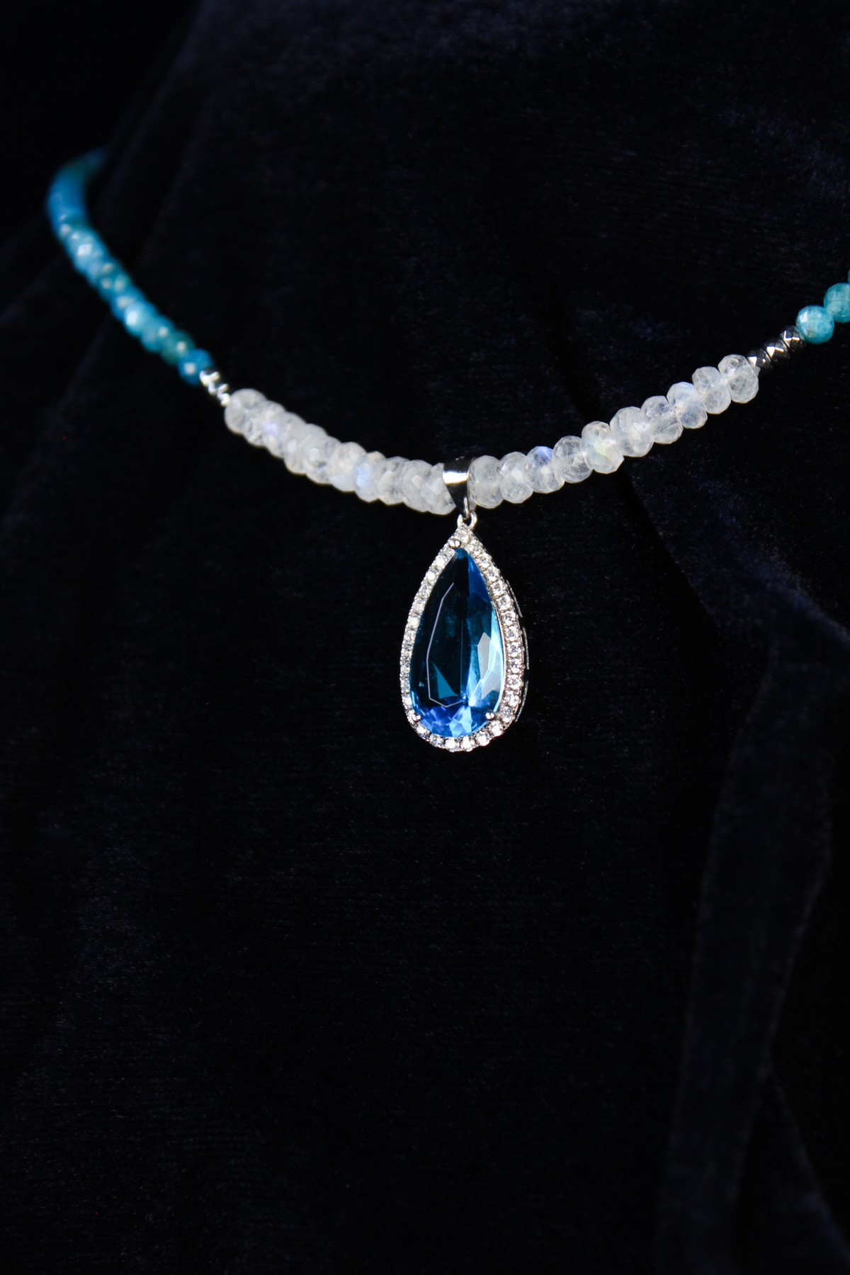 Sterling silver necklace with a teardrop blue apatite pendant surrounded by small diamonds and blue apatite and rainbow moonstone beads.