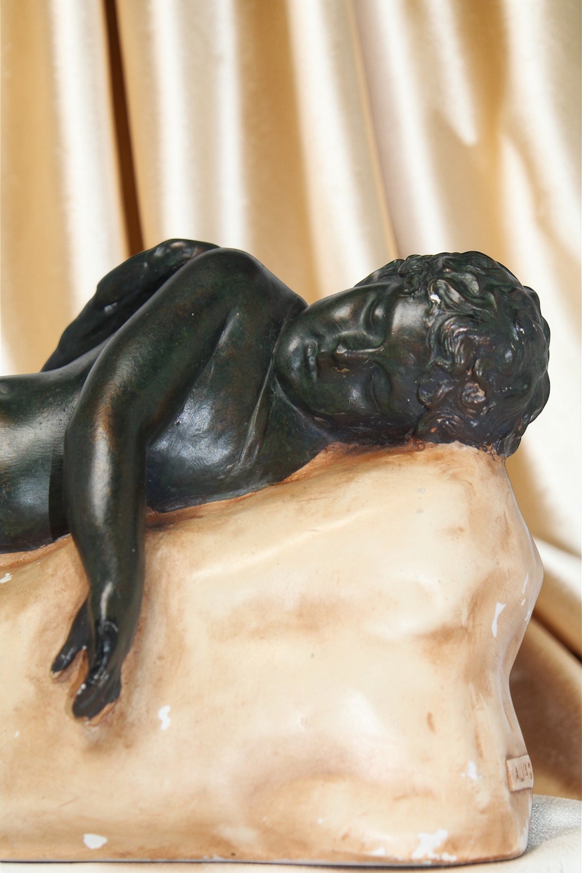 Vintage "The Sleeping Angel" sculpture of a reclining nude figure on a pale base.