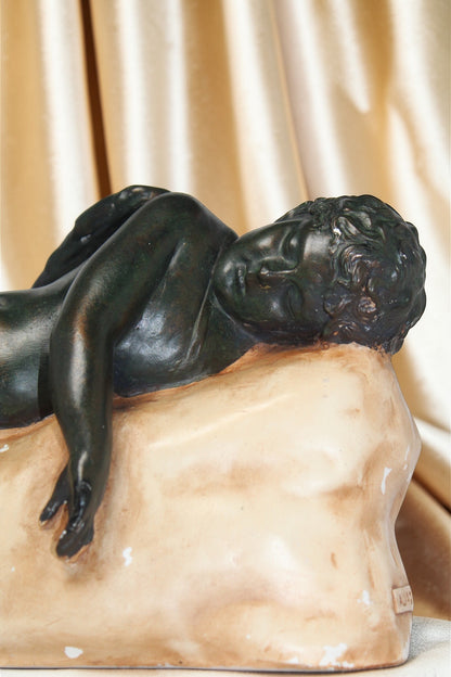 Vintage "The Sleeping Angel" sculpture of a reclining nude figure on a pale base.
