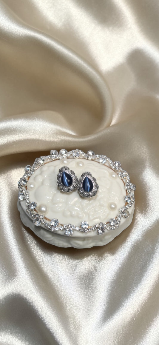 Jaestial blue fire vintage statement earrings with teardrop blue stones and diamond accents on a decorative box.