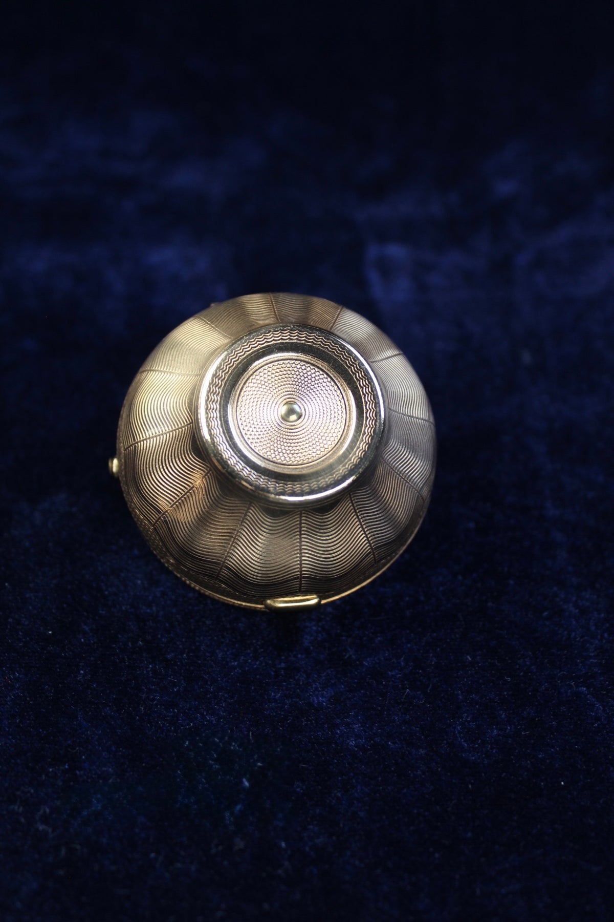 Gold-tone floral basket compact with intricate wavy line engraving.