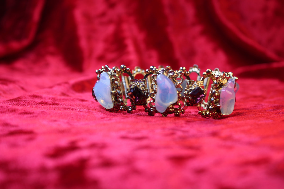 Gold tone bracelet with opalescent glass and garnet rhinestones in a Victorian Revival style.