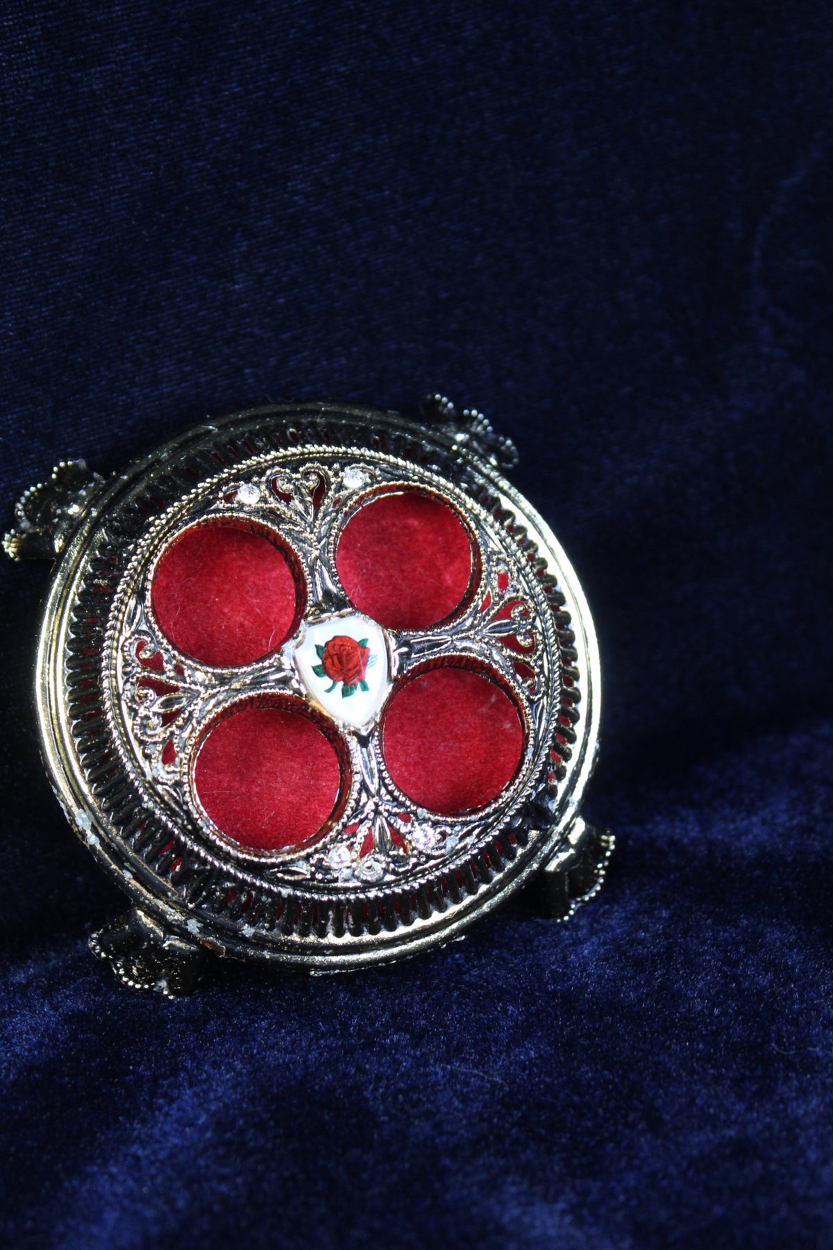 Vintage lipstick holder with ornate silver metalwork and red velvet compartments, featuring a rose emblem.
