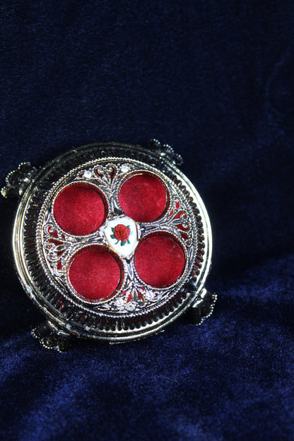 Vintage lipstick holder with ornate silver metalwork and red velvet compartments, featuring a rose emblem.