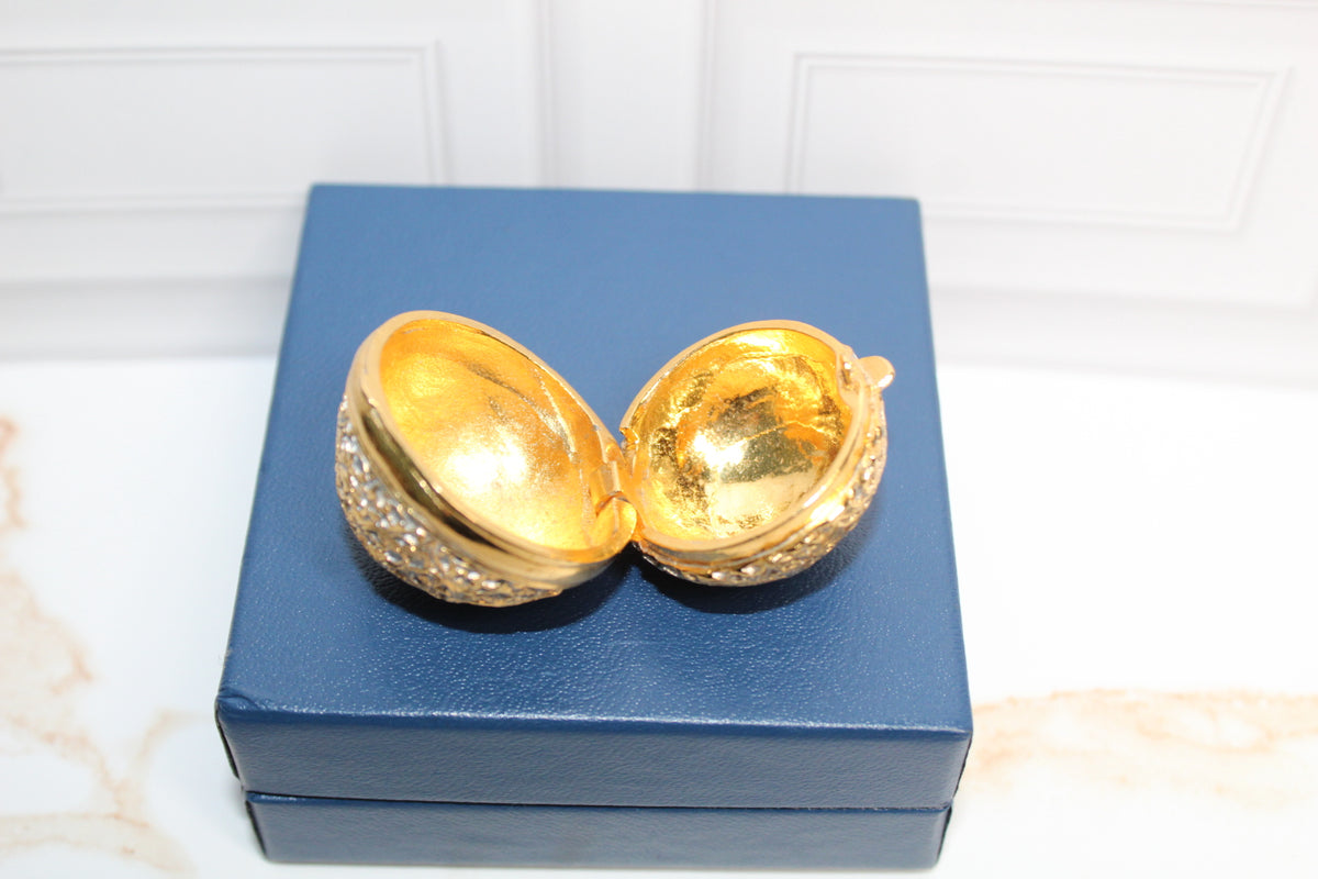 Jaestial Gilded Lace Round Trinket Box, open to reveal gold interior, on a blue box.