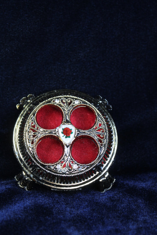 Gold-tone lipstick holder with red velvet lining and an enchanted rose emblem.