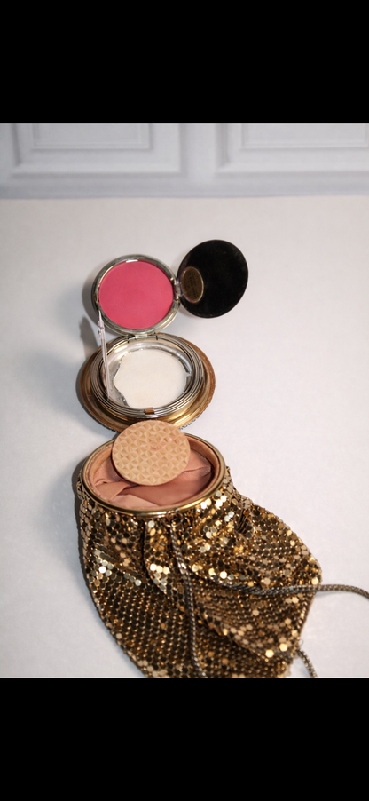 Vintage gold mesh purse compact with a pink blush and white powder inside.