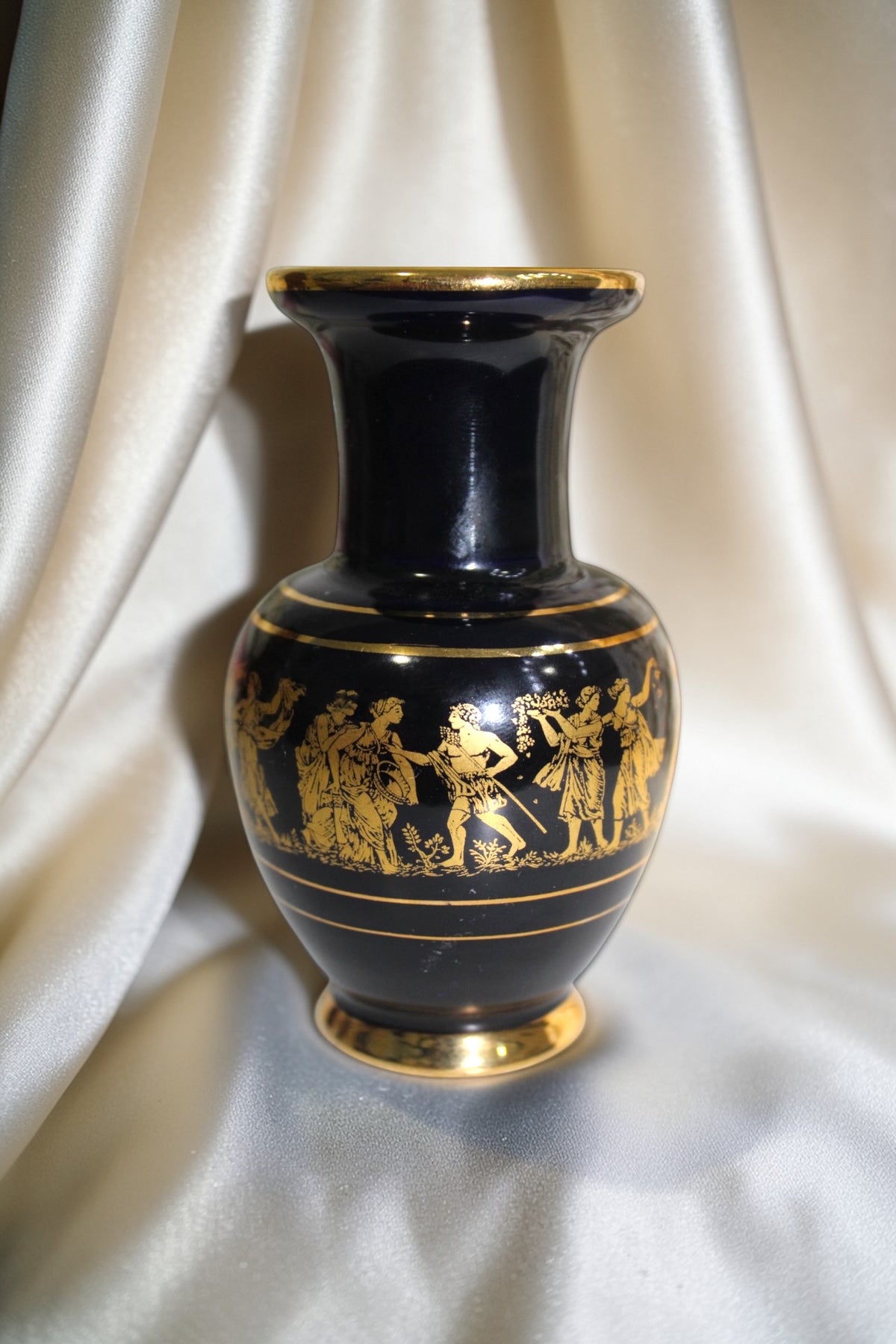 Black and gold miniature vase with Grecian procession motif, 5 inches tall.