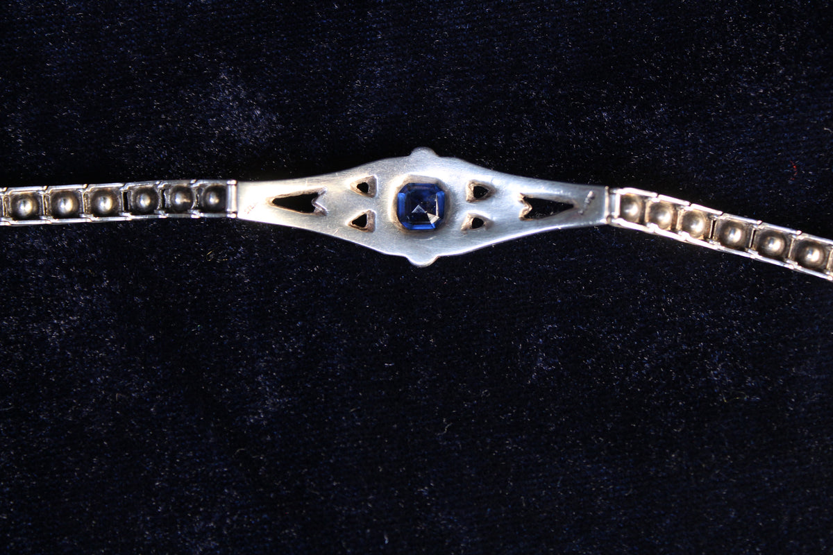 Sterling silver Art Deco bracelet with a central sapphire-blue paste stone and surrounding white paste stones.