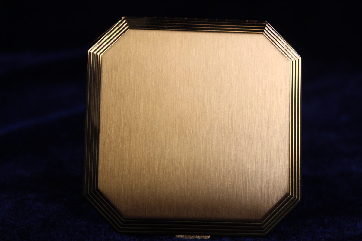 1950s Volupte octagonal gold-tone compact with stepped edges and a rhinestone clasp.