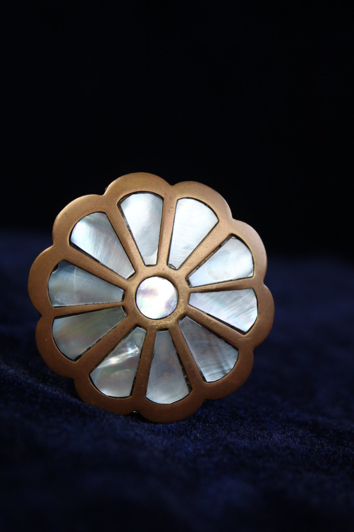Brass ring box with a floral design of mother-of-pearl petals and a central pearl.