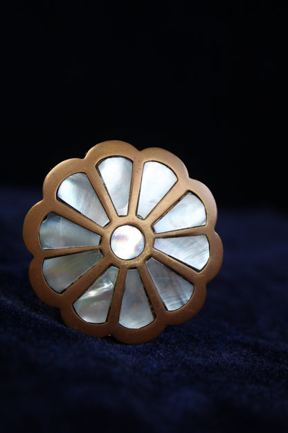 Brass ring box with a floral design of mother-of-pearl petals and a central pearl.