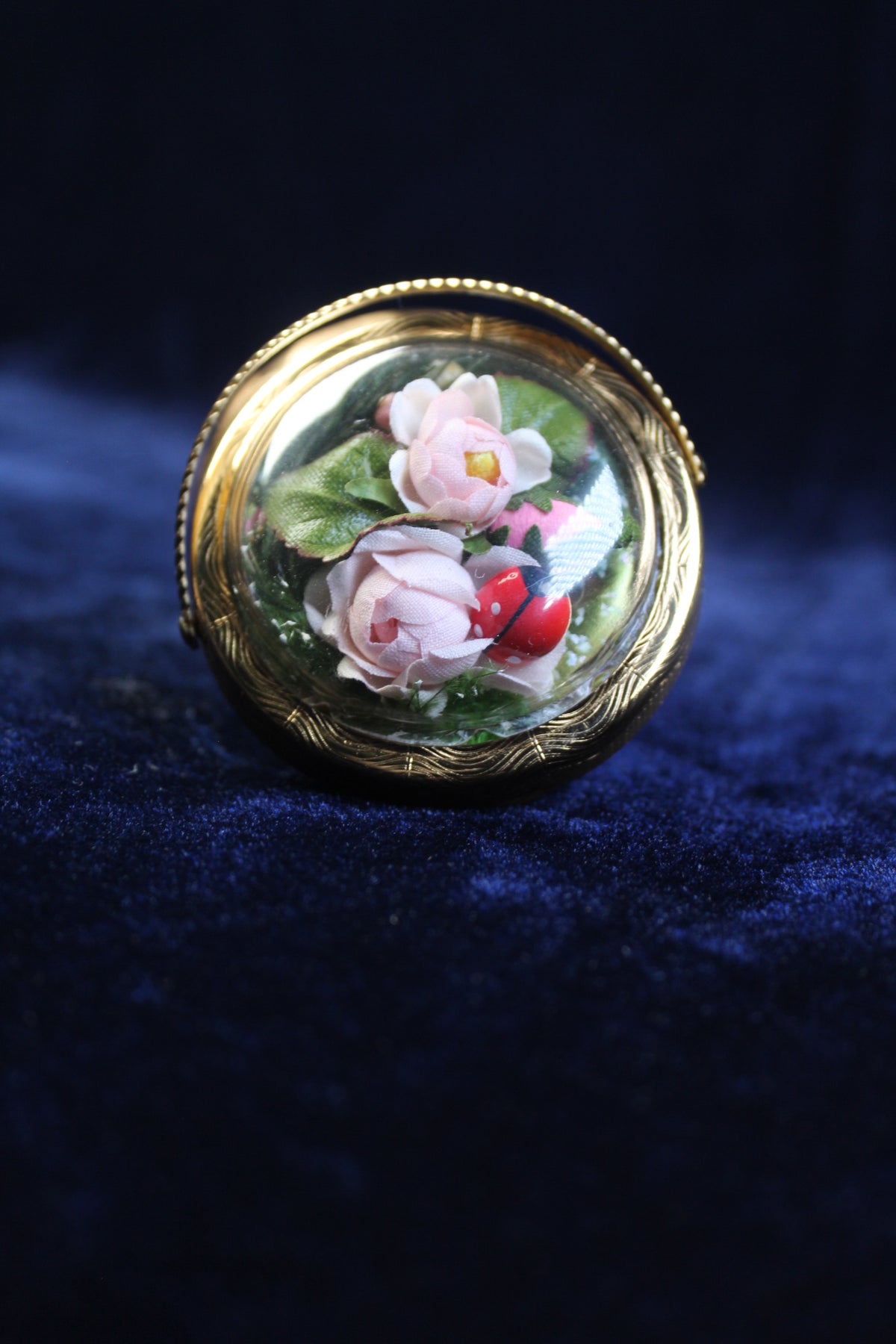 Gold-tone basket compact with a clear dome showcasing pink roses and a ladybug.