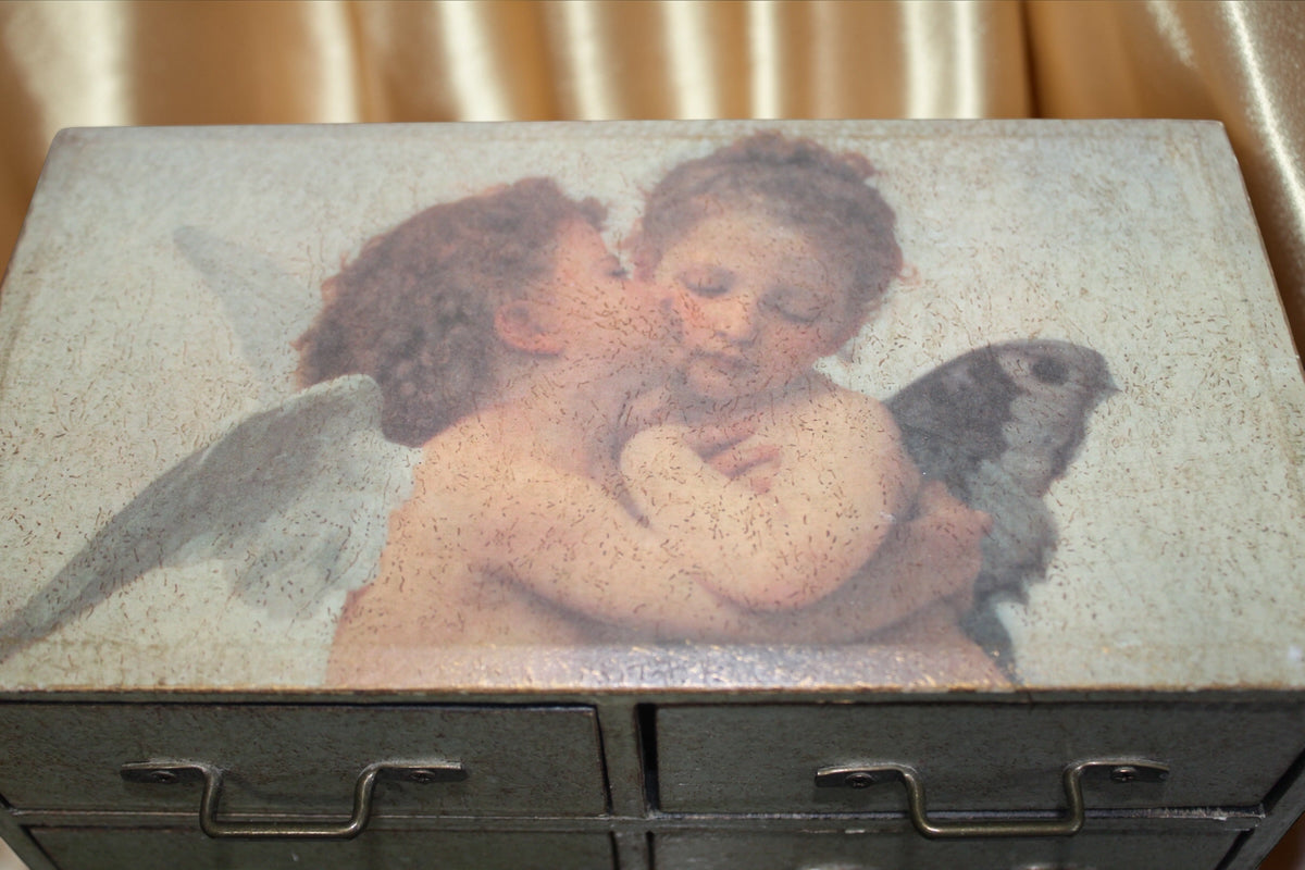 Vintage drawer chest with a painting of two cherubs and a bird on the lid.