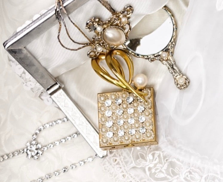 Vintage clutch adorned with sequins and pearls, next to a small mirror and jewelry.