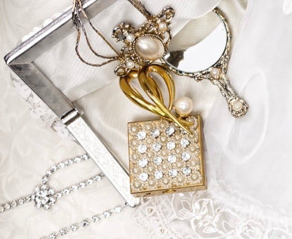 Vintage clutch adorned with sequins and pearls, next to a small mirror and jewelry.