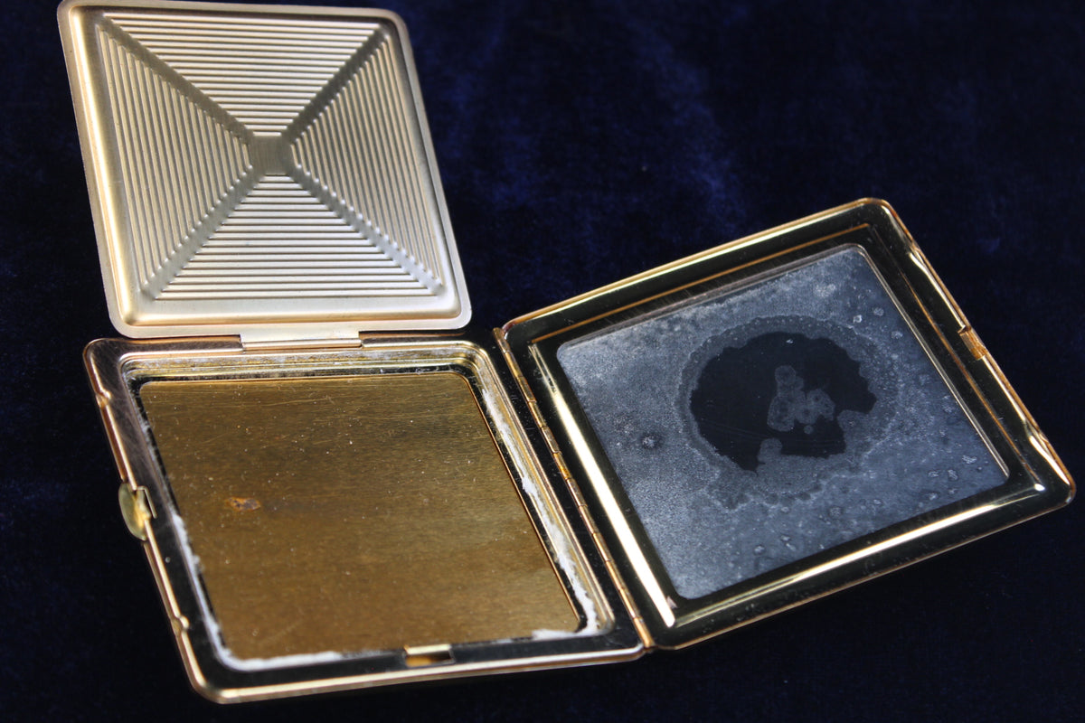 1940s gold tone vanity compact, open, showing engraved lid and powder compartment.