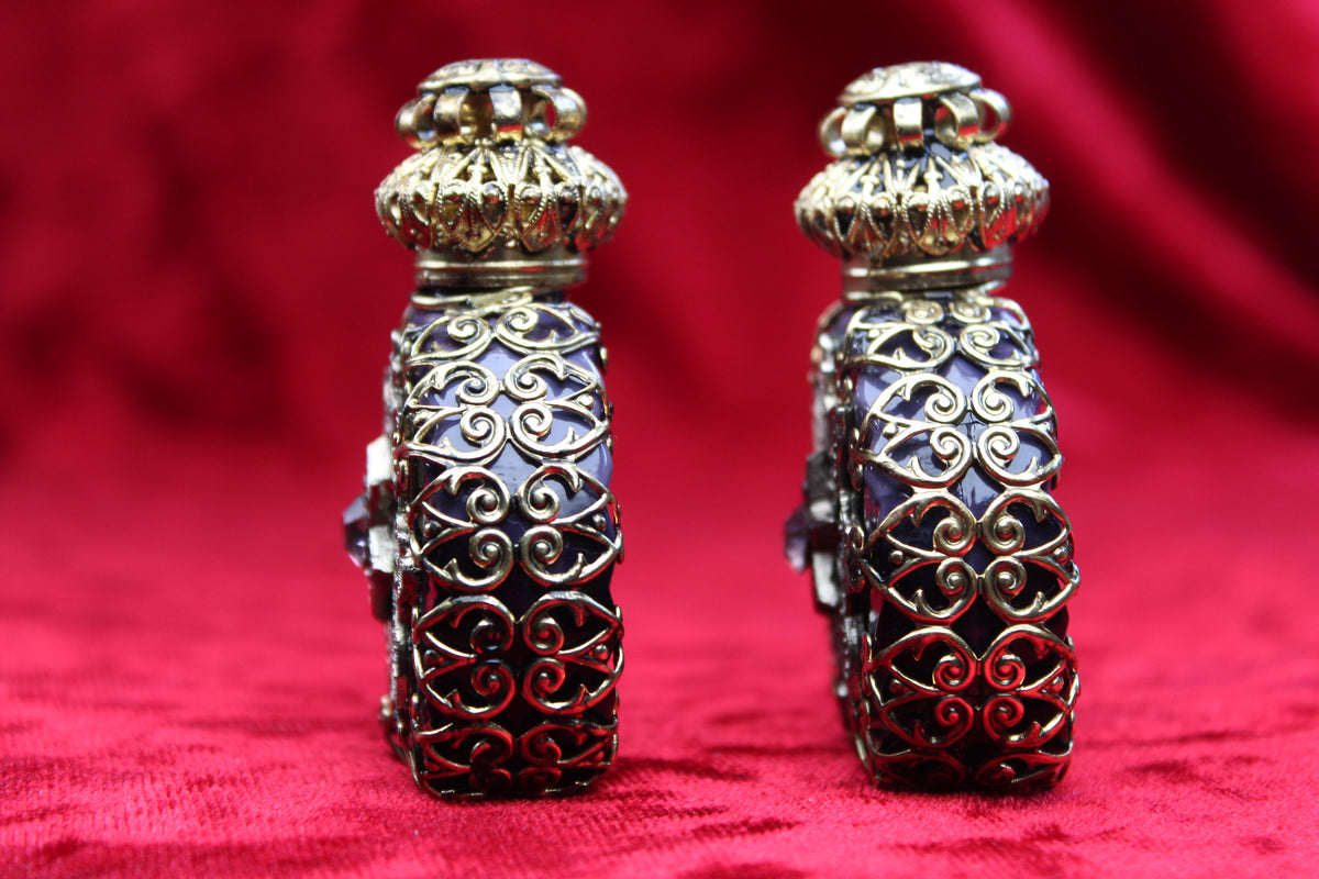 Matched pair of vintage amethyst glass perfume bottles with gold-tone filigree and rhinestone details.