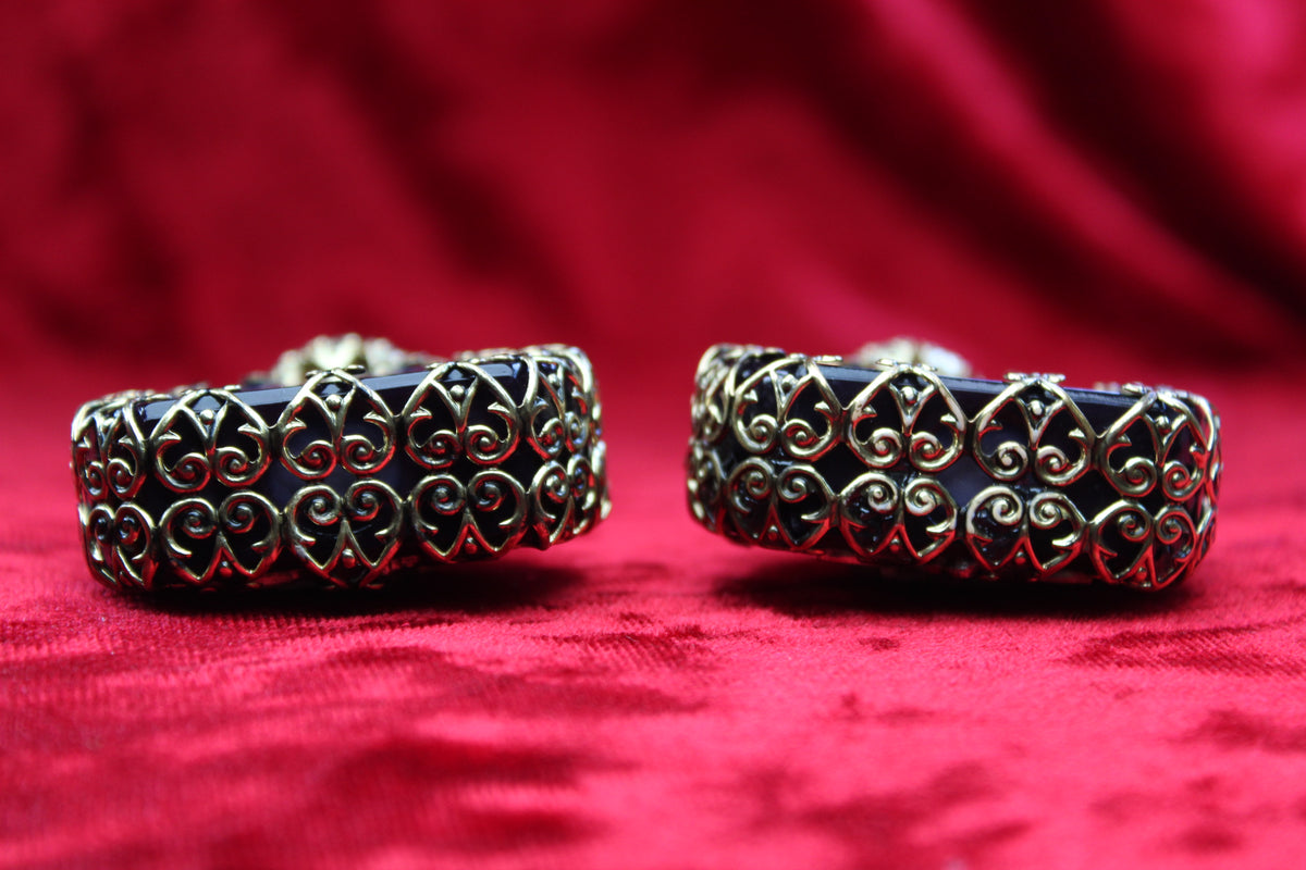 Matched pair of amethyst glass perfume bottles with gold-tone filigree, on a red velvet background.
