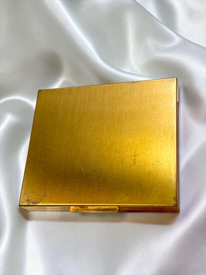 Vintage Ritz gold-tone powder compact with rhinestone floral detail, showing patina and wear.