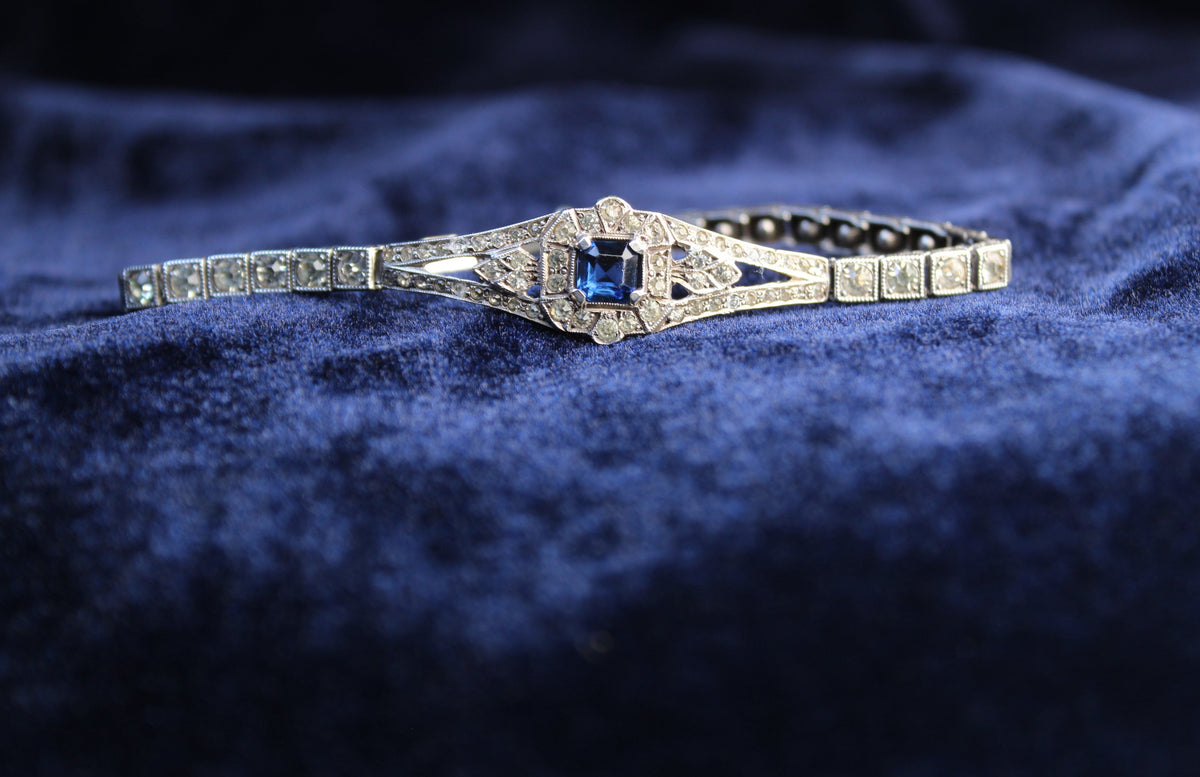 Sterling silver Art Deco bracelet with a central sapphire blue paste stone and surrounding white paste stones.