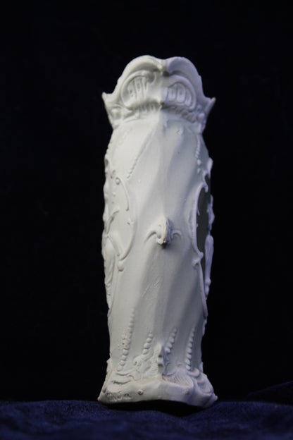 White Art Deco vase with intricate raised floral and scroll details, on a dark background.
