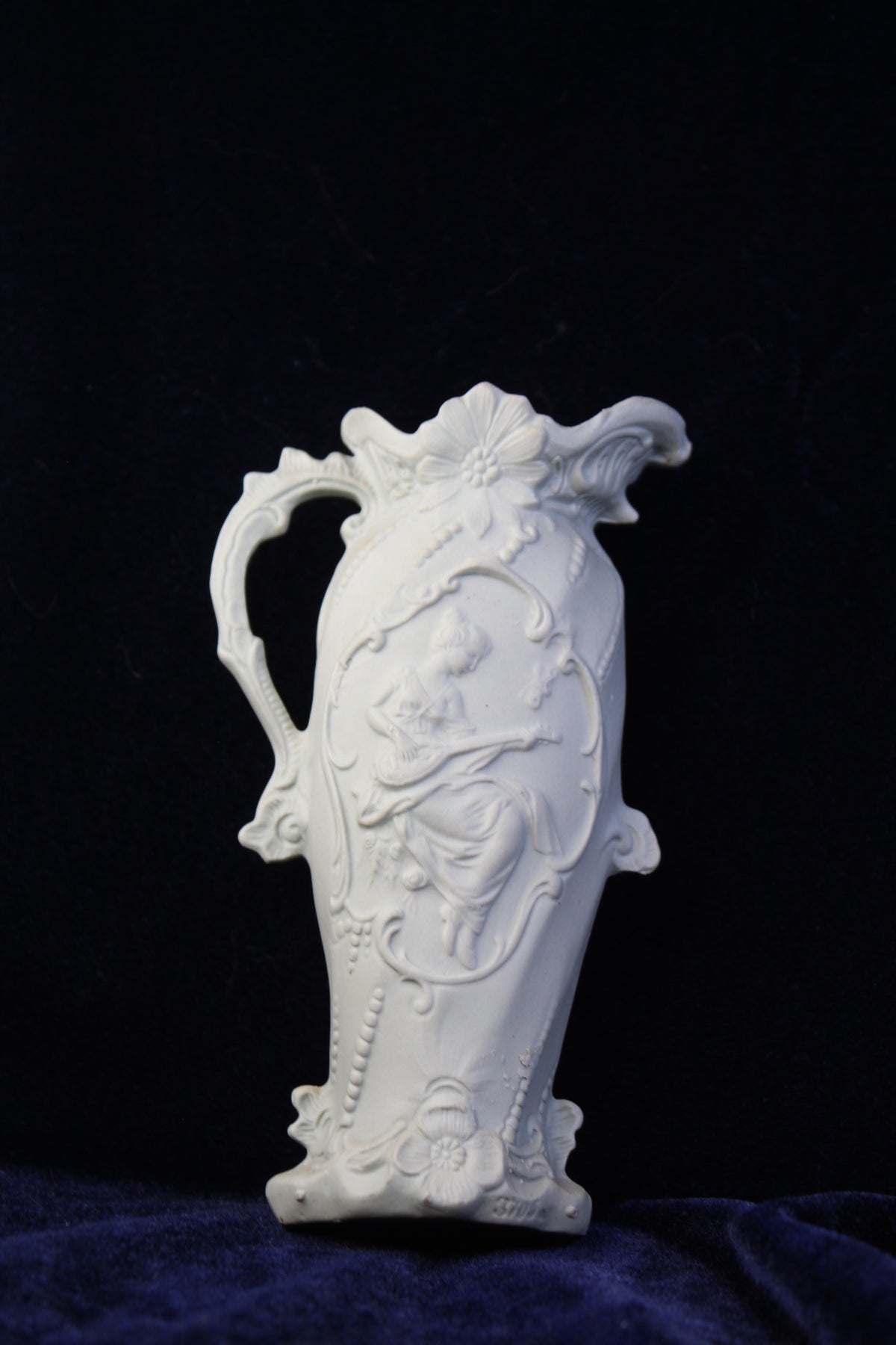 White jasperware-style vase with embossed relief of a woman playing a lute.