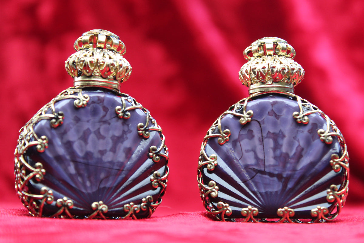 Matched pair of vintage amethyst glass perfume bottles with gold filigree and crown stoppers.