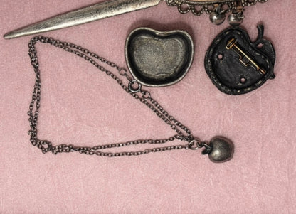 A vintage apple-shaped trinket box with a hidden necklace and a brooch.