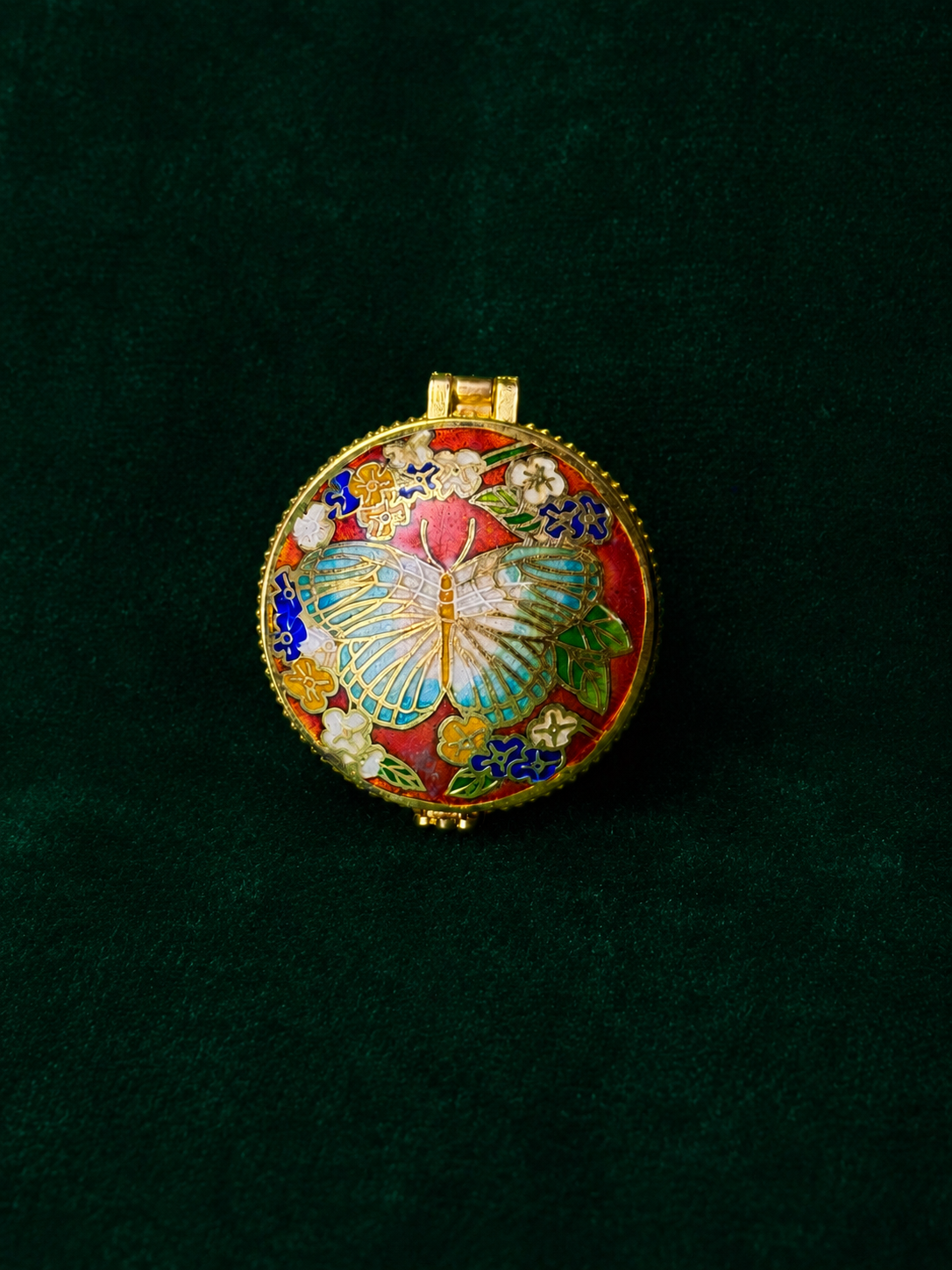 Round orange-red cloisonné trinket box with a butterfly and floral design.