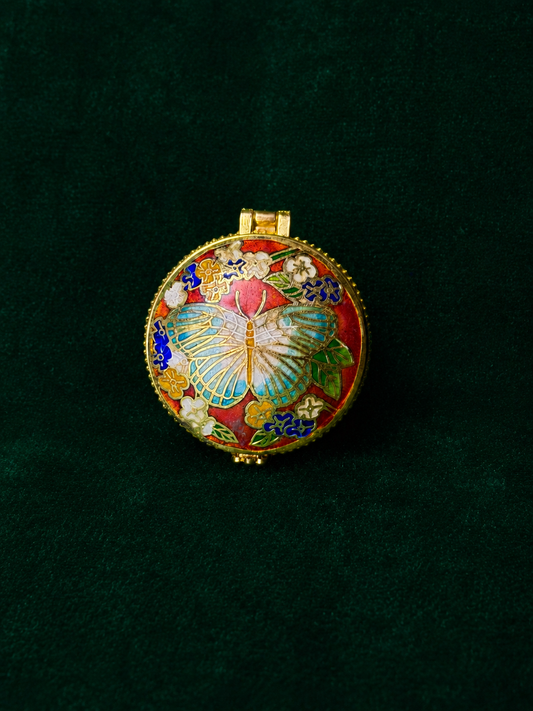 Round orange-red cloisonné trinket box with a butterfly and floral design.