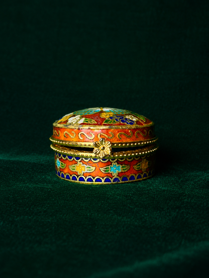 Orange red enamel cloisonné trinket box with butterfly and floral designs on a dark green velvet background.
