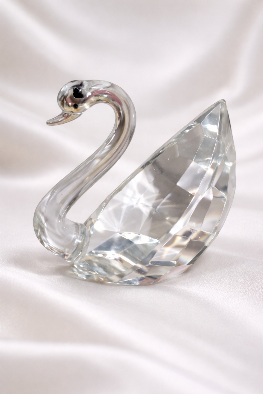 Faceted glass crystal swan figurine with a curved neck, reflecting light.