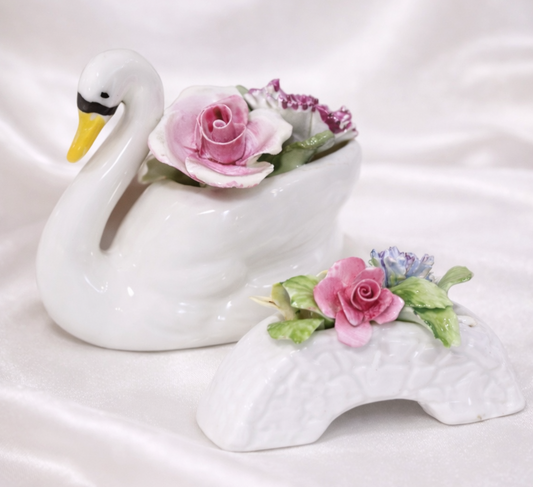 Vintage porcelain swan with pink roses and a floral bridge with pink and blue flowers.