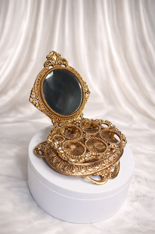 Gold-tone lipstick holder with an oval mirror and crystal accents, featuring multiple wells for lipstick organization.