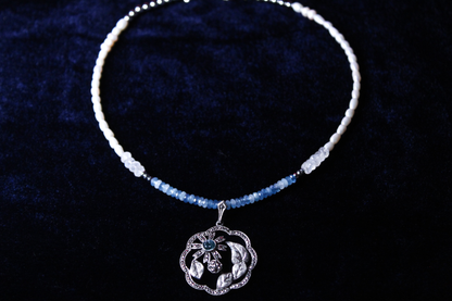 Sterling silver pendant necklace with aquamarine and moonstone beads on a dark blue background.