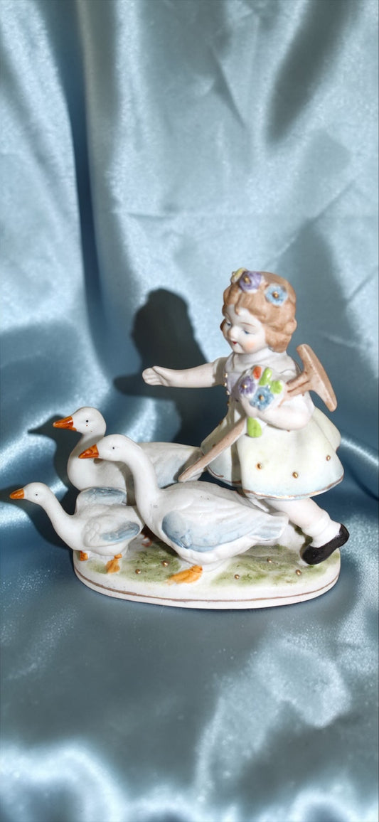 1950s porcelain figurine of a girl with flowers in her hair leading three geese.